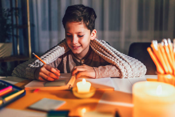 Little boy studying  with a burning candle. stock photo