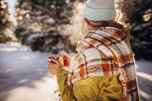 One woman, young woman enjoying a hot tea on mountain alone during winter days.