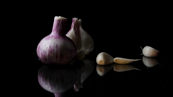 Onions and garlic over black background. Still-life of onions and falling garlic on black background.