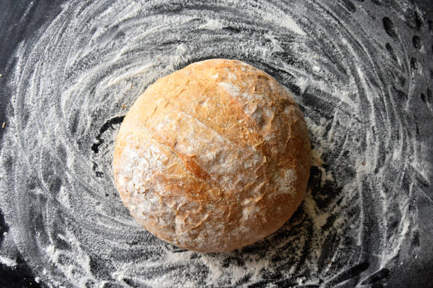 Round white bread with flour on kitchen table top view