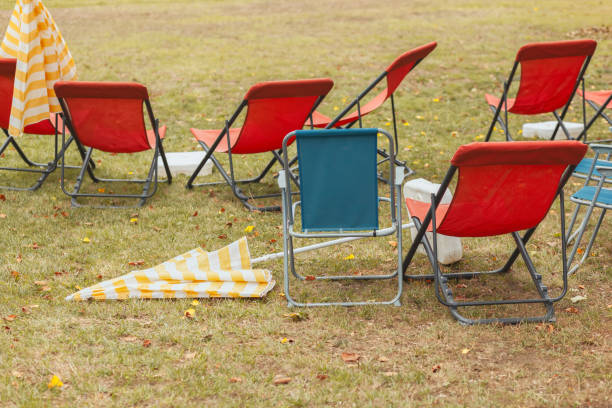 istock Red and blue foldable canvas chairs, empty, and closed striped parasols, end of summer concept 1427542492