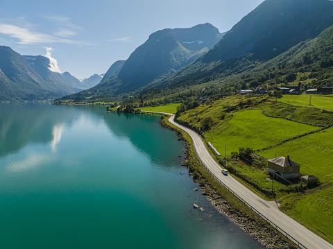 Scenic aerial view of car on the road near turquoise  lake in Norway