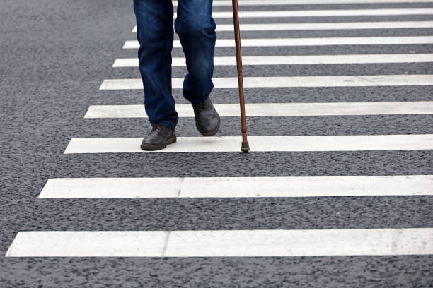 Man walking with a cane on crosswalk