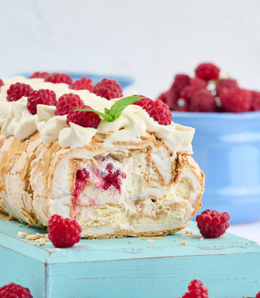 istock Baked meringue roll with cream and fresh red raspberry, white background 1427546125