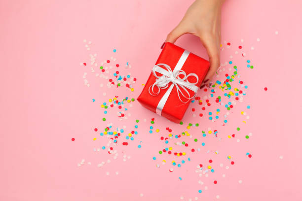 istock Woman holding gift box on color background 1427546682