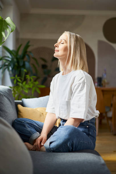 Mindfulness concept. Adult woman sitting on the couch with closed eyes. stock photo