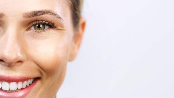 Half face portrait, beauty and woman on a grey studio background mockup. Closeup, happy girl and glowing smooth skin after a facial spa treatment for wellness, skincare and body care with a smile. Half face portrait, beauty and woman on a grey studio background mockup. Closeup, happy girl and glowing smooth skin after a facial spa treatment for wellness, skincare and body care with a smile. clear skin stock pictures, royalty-free photos & images