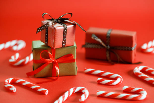 Christmas background with gift boxes and red candy canes  on red background. Closeup.