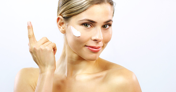 Skin care, cream lotion and woman and product on her face or cheek with white studio background mock up or copy space. Young beauty model facial and hand portrait with antiaging routine and skincare