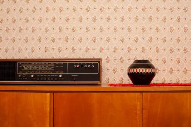 vintage sideboard with radio and vase in front of wallpaper