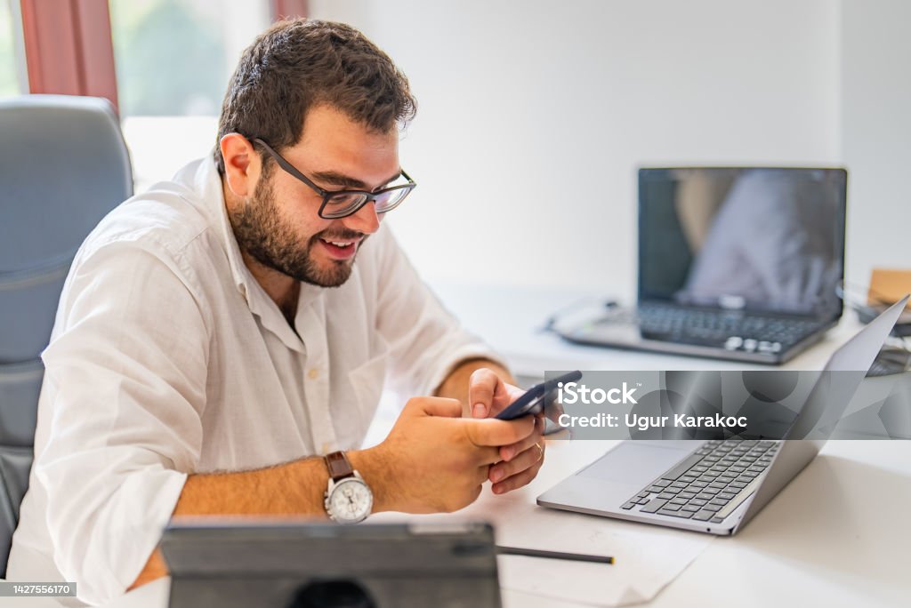 Young businessman using smartphone at his office desk Man working at his desk in the office Online Messaging Stock Photo