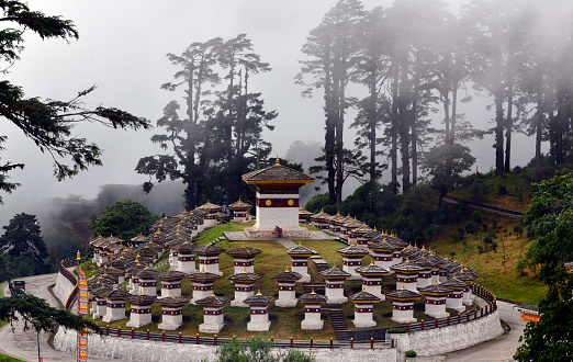 Dochula mountain pass, Himalayas, Bhutan: misty forest and the  Druk Wangyal Chortens, 108 memorial chortens in three layers - 108 is an auspicious number in Buddhism, it stands for the Kangyur, the Tibetan Buddhist canon - the stupas mark the victory of of the Royal Bhutanese Army against Assamese insurgents from India in 2003.