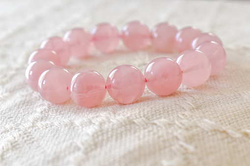 Rose quartz bracelet on fabric background.  Love magnet, unconditional love, forgiveness and compassion crystal gemstone. Healing and kindness stone.