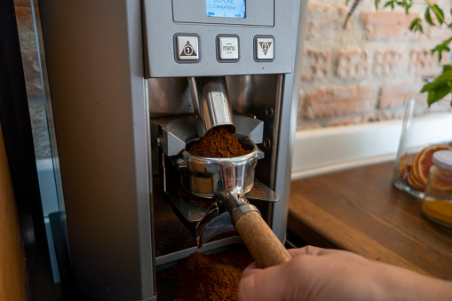 Freshly ground coffee pouring into portafilter in espresso machine