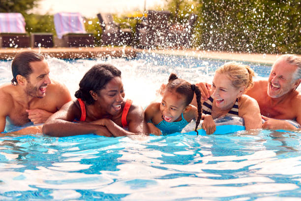 família multigeragração sorridente nas férias de verão relaxando na piscina no airbed - swimming swimming pool senior adult child - fotografias e filmes do acervo