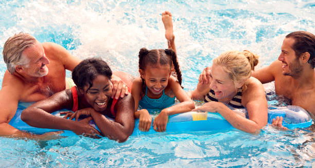 família multigeragração sorridente nas férias de verão relaxando na piscina no airbed - swimming swimming pool senior adult child - fotografias e filmes do acervo