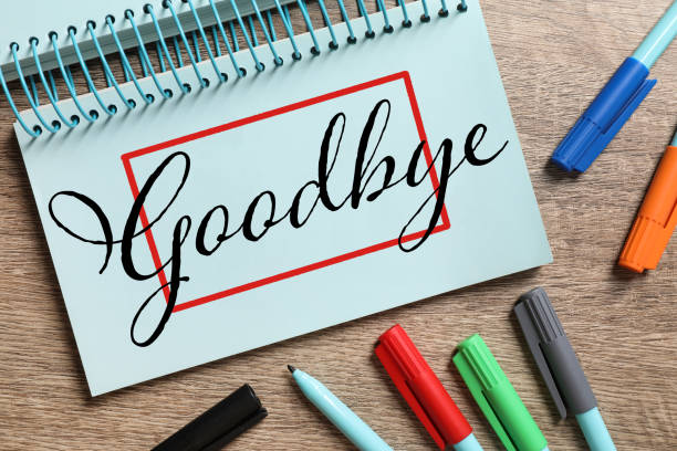 istock Notebook with word Goodbye and markers on wooden table, flat lay 1427565515