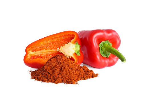 Fresh bell peppers and paprika powder on white background