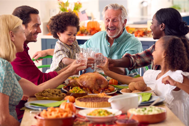 wielopokoleniowa rodzina świętująca święto dziękczynienia w domu, jedząc posiłek i wiwatując wodą - middle eastern ethnicity zdjęcia i obrazy z banku zdjęć