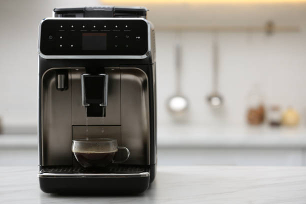 Modern electric espresso machine making coffee on white marble countertop in kitchen