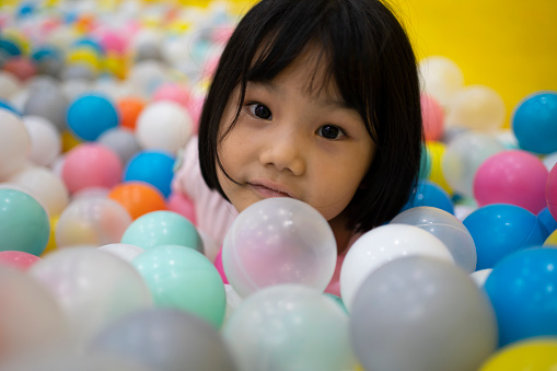 Happy little girl playing in colorful plastic ball pool