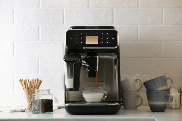 istock Modern espresso machine pouring coffee into glass cup with milk on white countertop in kitchen 1427570130