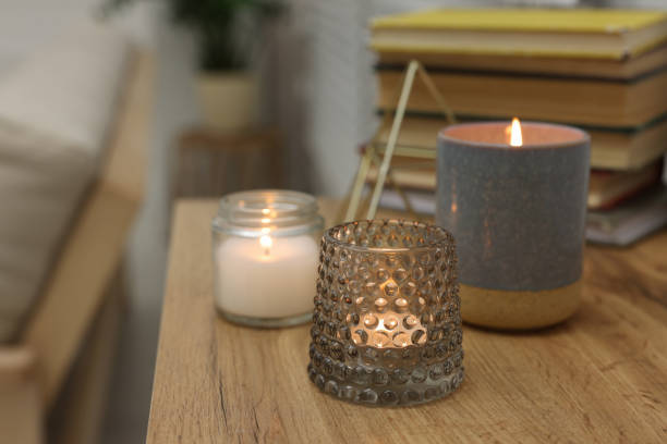 istock Lit candles in different holders on wooden table indoors. Space for text 1427571587