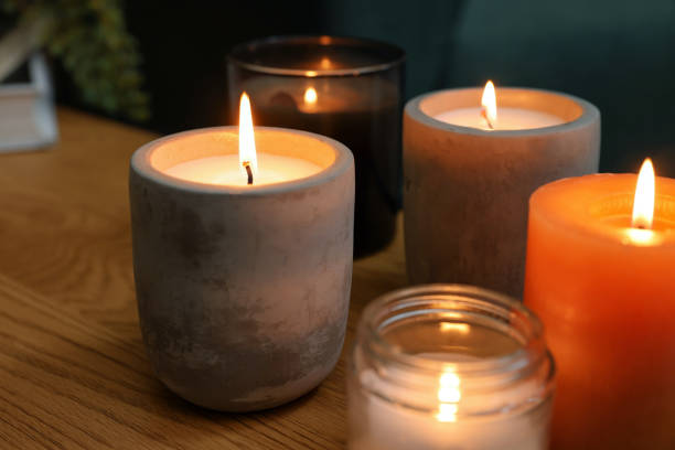 istock Lit candles in different holders on wooden table indoors 1427571629