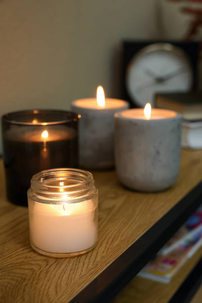 istock Lit candles in different holders on wooden table indoors. Space for text 1427572063