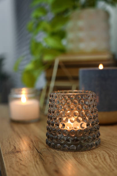 istock Lit candles in different holders on wooden table indoors. Space for text 1427572072