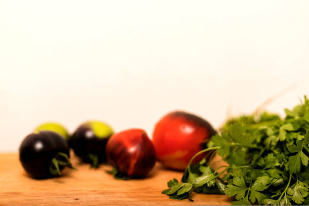 Red and black tomatoes next to parsley lie in the kitchen on a wooden table. Fresh autumn vegetables
