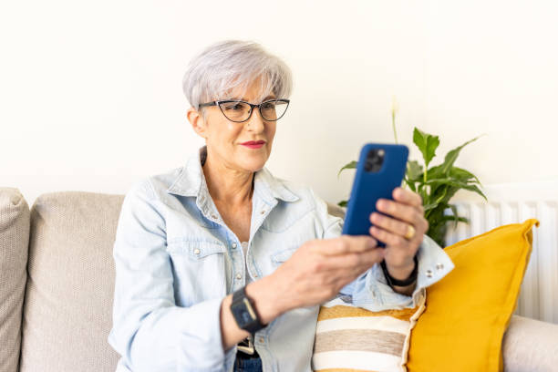 istock Senior woman using mobile phone at home sitting on the sofa 1427574046