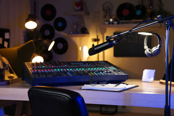 istock Microphone near table with professional mixing console in radio studio 1427577724