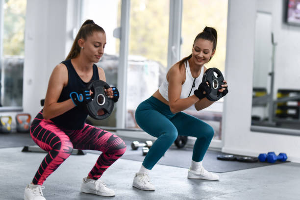 istock Two Female Athletes Doing Weight Squats In Gym 1427578602