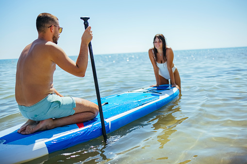 Couple of tourists young man and woman having fun paddleboarding