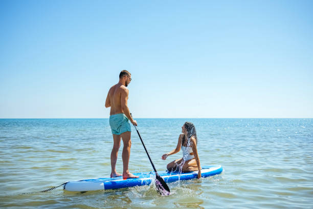 Beach fun couple on stand up paddleboard stock photo