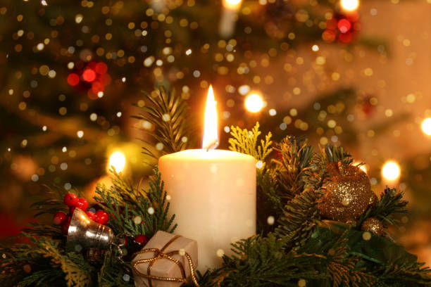 concetto di natale - candela dell'avvento lunatica di fronte all'albero di natale decorato - advent wreath foto e immagini stock
