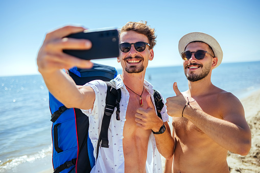 Two friends on the beach taking a selfie together