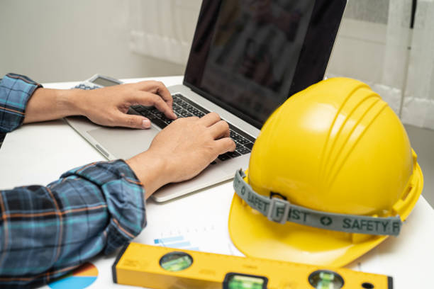 istock Asian engineer with architectural house plan project blueprint, graph and yellow helmet and engineering construction tools. 1427583960