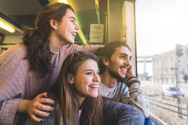Happy group of friends looking out of train window stock photo