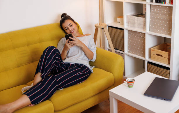istock Smiling young woman texting at home 1427591593
