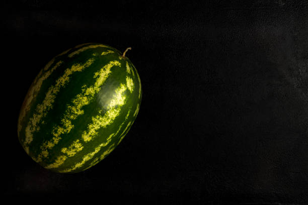 Green watermelon on a dark background. Top view, copy space, healthy food