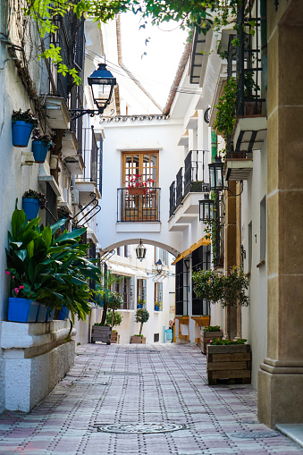 Small street of Marbella with an arch and flower pots on the walls
