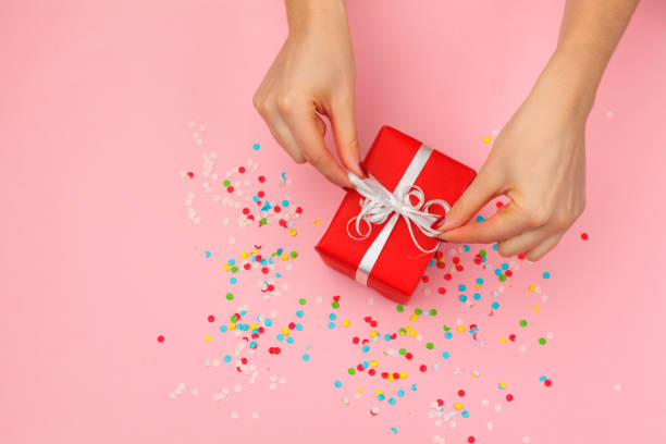 istock Woman holding gift box on color background 1427595279