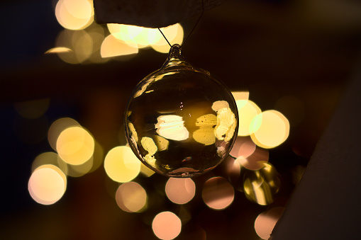 transparent glass christmas ball, with a yellow bokeh background. christmas decoration in the dark