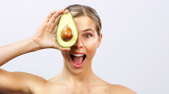 Health, avocado wellness and eating healthy of a woman with a happy face and smile. Portrait of a excited female or nutritionist positive about weight loss, green diet food and natural fruit vitamins