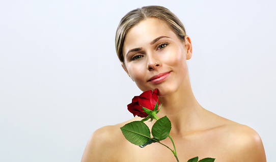 Beautiful woman holding long stem red rose close to face, red lips, romantic concept