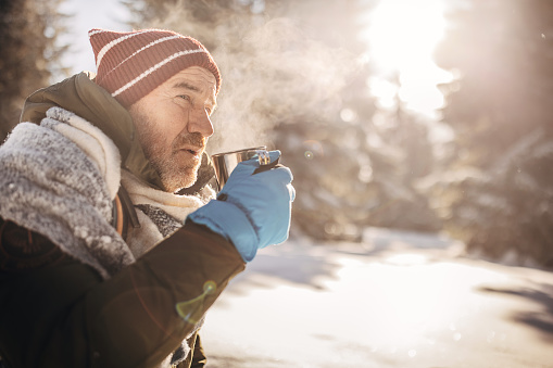 One man, mature man drinking hot tea on the mountain alone during winter days.
