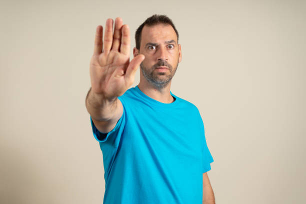 istock Handsome man in his 40s over beige wall with open hand making stop sign with serious and confident expression, defense gesture. 1427604557