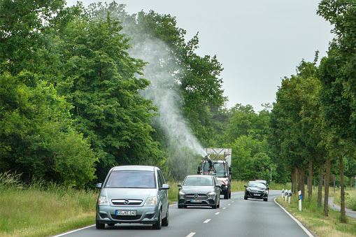 Trevor, Germany - May 23, 2022: Biological pest control. A truck is spraying pesticides on trees on a federal road nearby Trebur in Germany